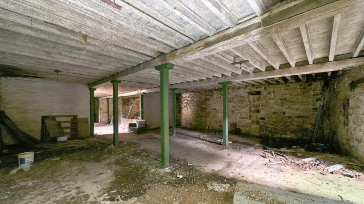 Shepherd An empty building with green pillars holding up a wooden roof