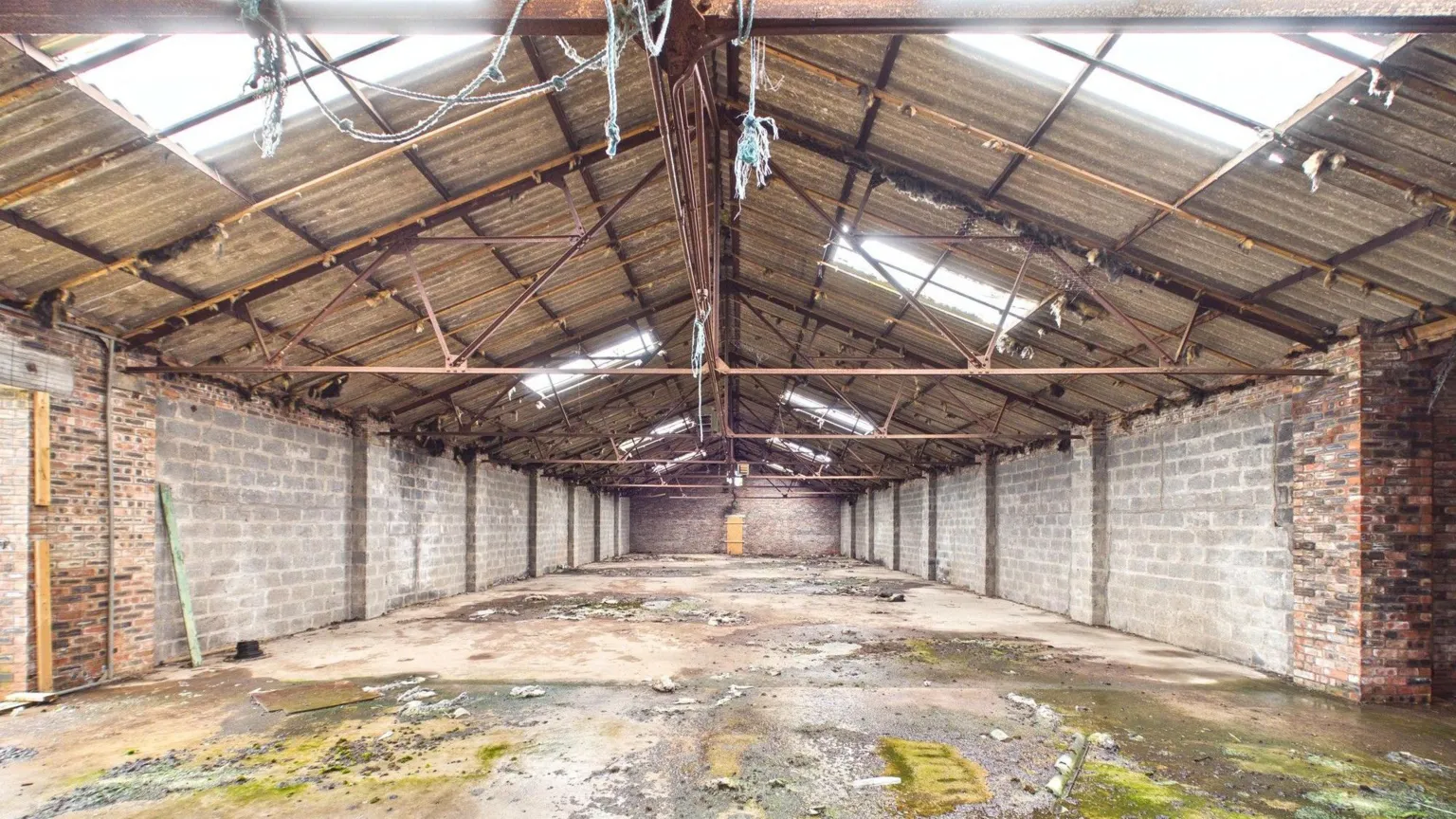 Shepherd A large empty warehouse with metal bars across the roof and panel windows