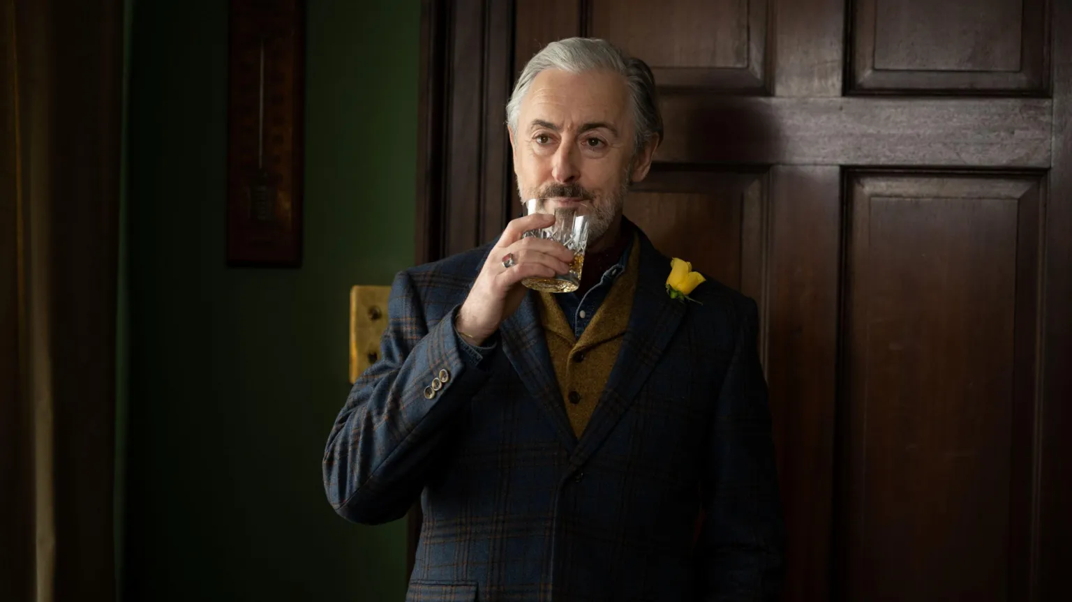 Lisa Birch A dark wooded, stylish room is the backdrop for a dramatic moody shot of Alan Cumming, in a tartan blazer, brown tweed waistcoat and denim shirt, lifting a glass of whisky to his lips.