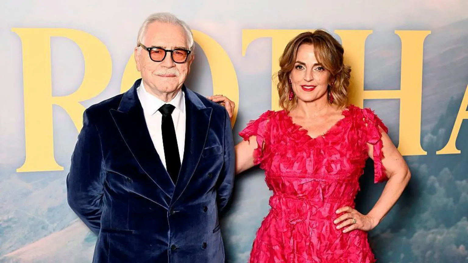 Cox and his wife Nicole Ansari Cox at the premier of Glenrothan - Brian is in a navy velvet blazer and Nicole wears a vibrant red dress.