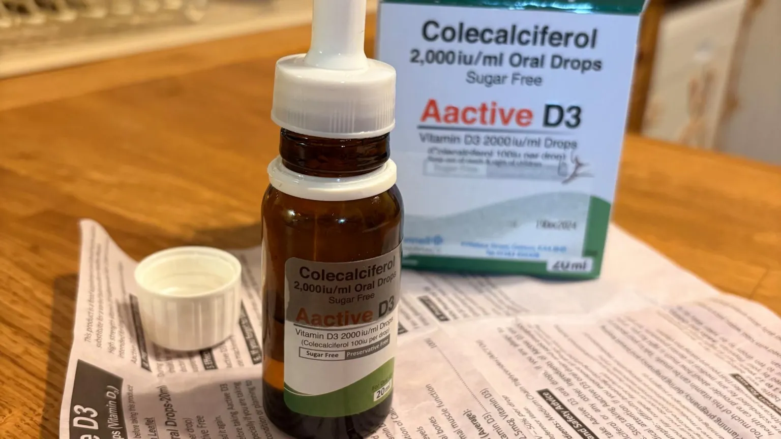 A bottle of vitamin D3 oral drops labelled “Aactive D3”, shown with its packaging and leaflet on a table.