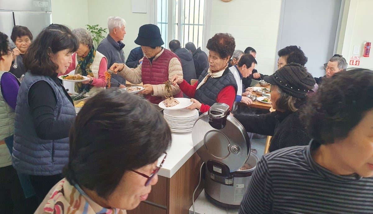 People in Guyang-ri enjoy a free communal meal in a village hall