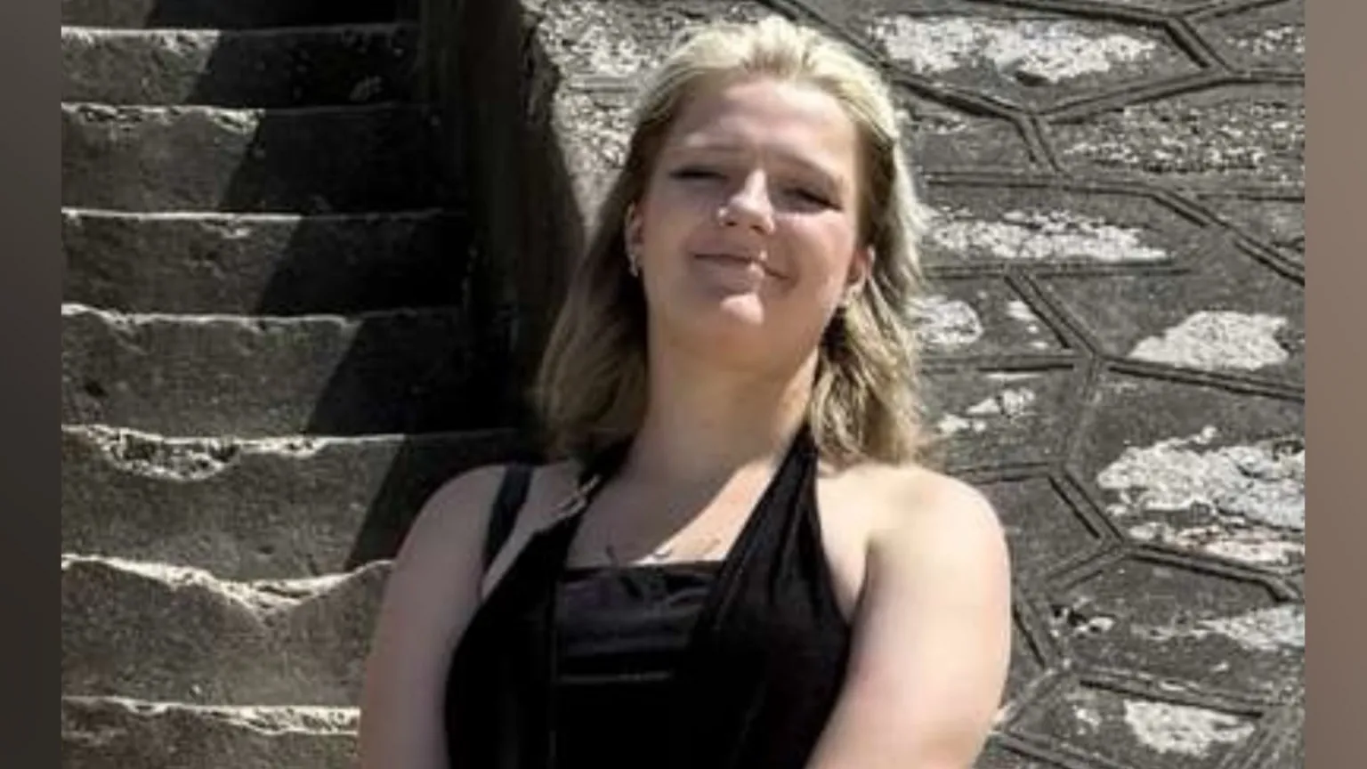 Giselle Bartram Giselle Bartram smiles at the camera. She has brown and blonde hair. She is wearing a black dress.