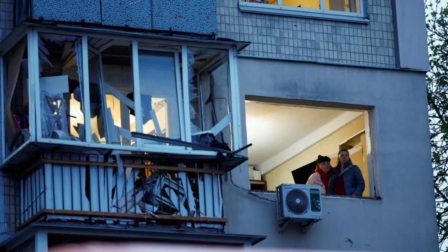  Two women look out of a window of an apartment block at the site of a Russian missile strike in Kyiv