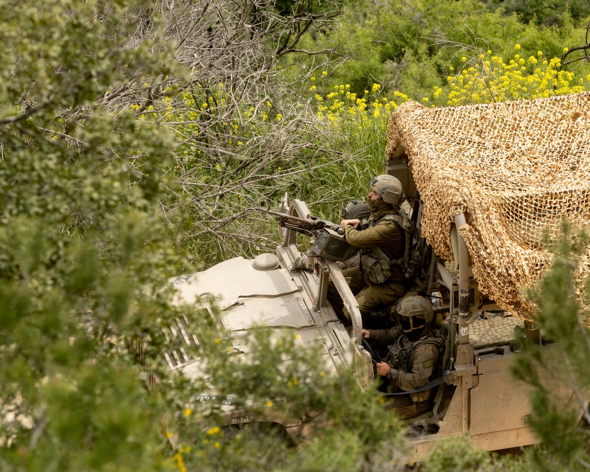 An Israeli soldier sits in an army vehicle as it mover near the border with Lebanon, as seen from a position on the Israeli side of the border.