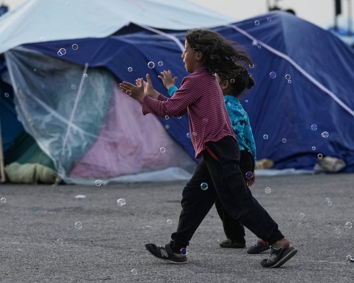 Girls chase bubbles next to their family’s tents used as shelter after fleeing Israeli bombardment in Beirut’s southern suburbs
