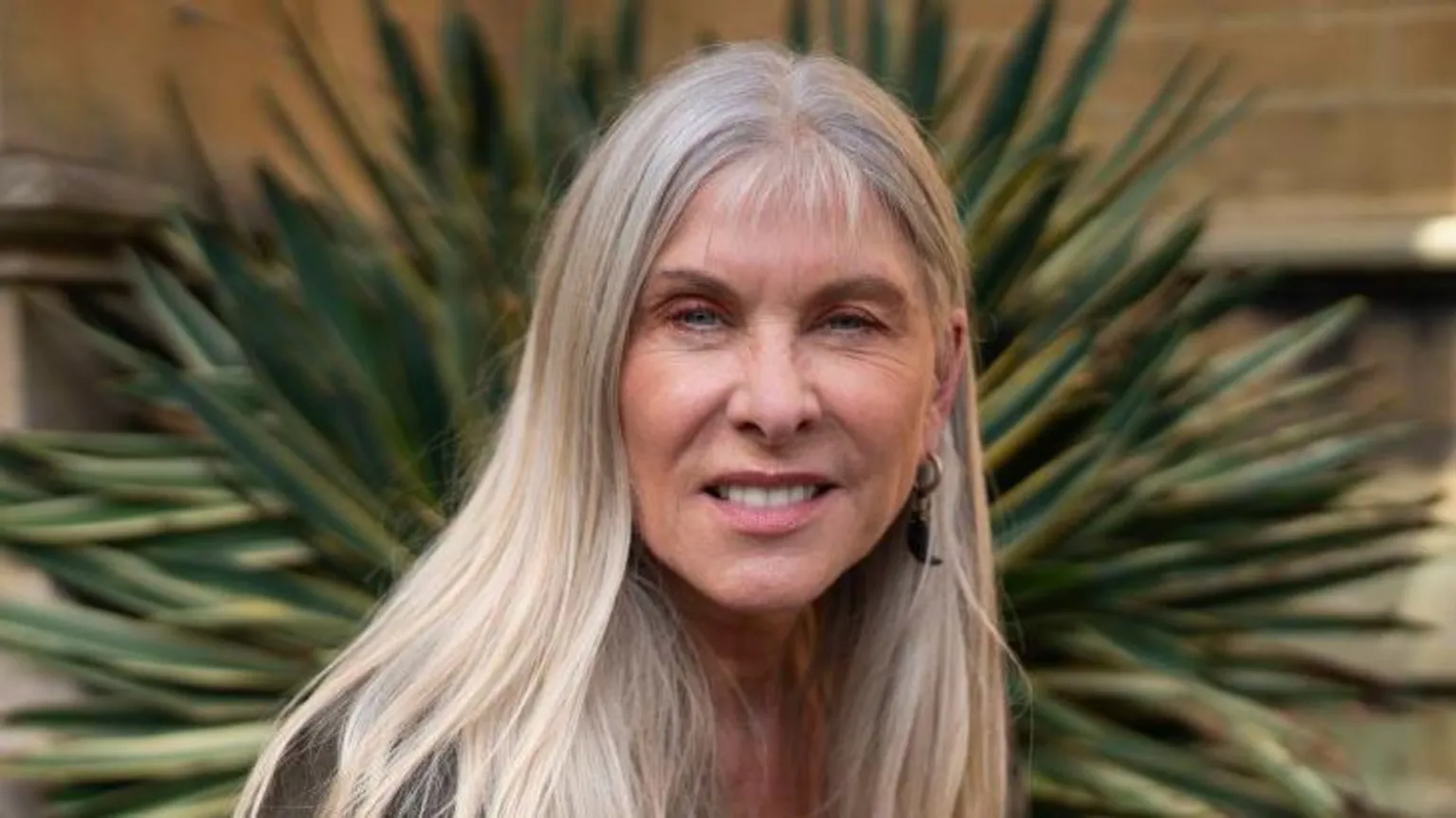 Sharron Davies has long, blonde hair. She is smiling at the camera