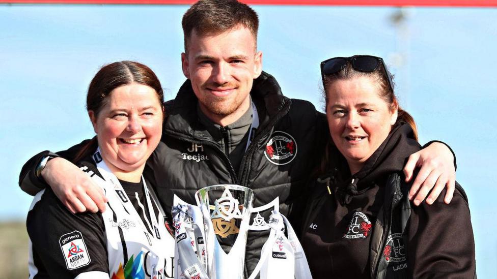 Jordan Hadaway with two Llandudno Ladies FC players and the Cymru North trophy