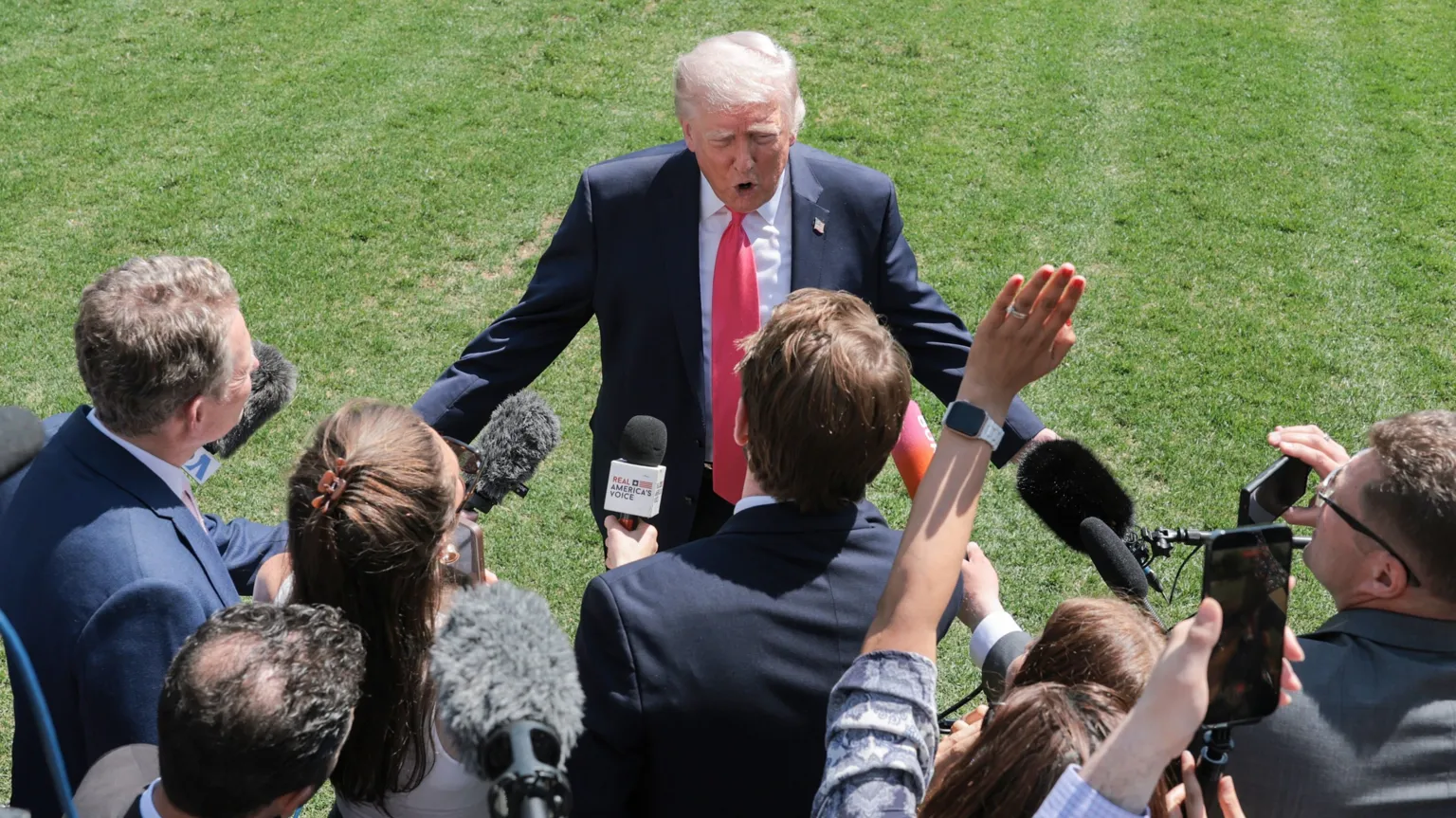  US President Donald Trump, wearing a dark suit and red tie, speaks to the media on the South Lawn of the White House