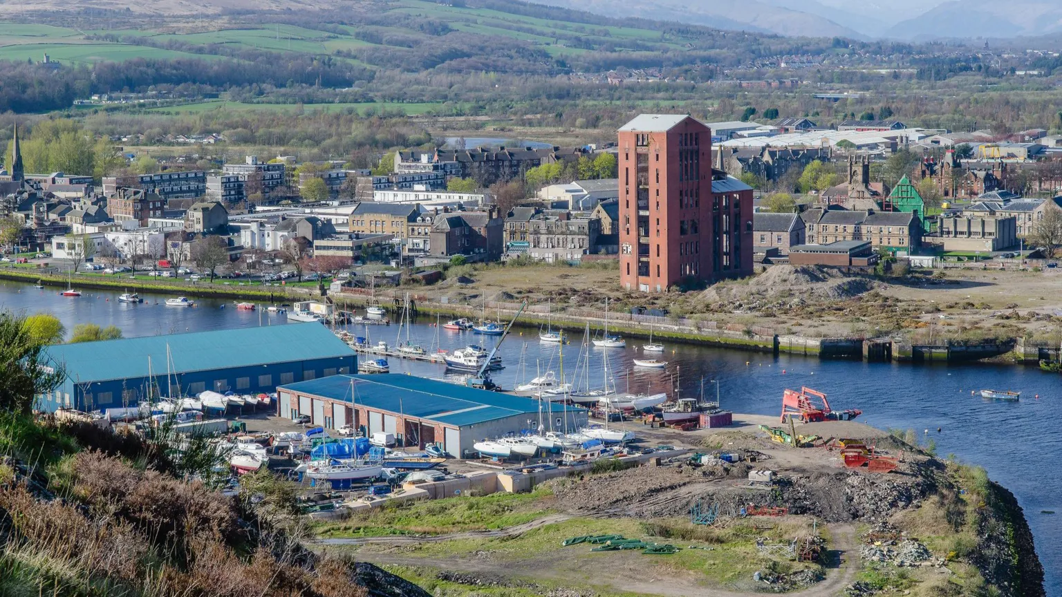  An image of Dumbarton's waterfront, pictured from the top of Dumbarton Rock, including various industrial buildings as well as yachts along the waterfront