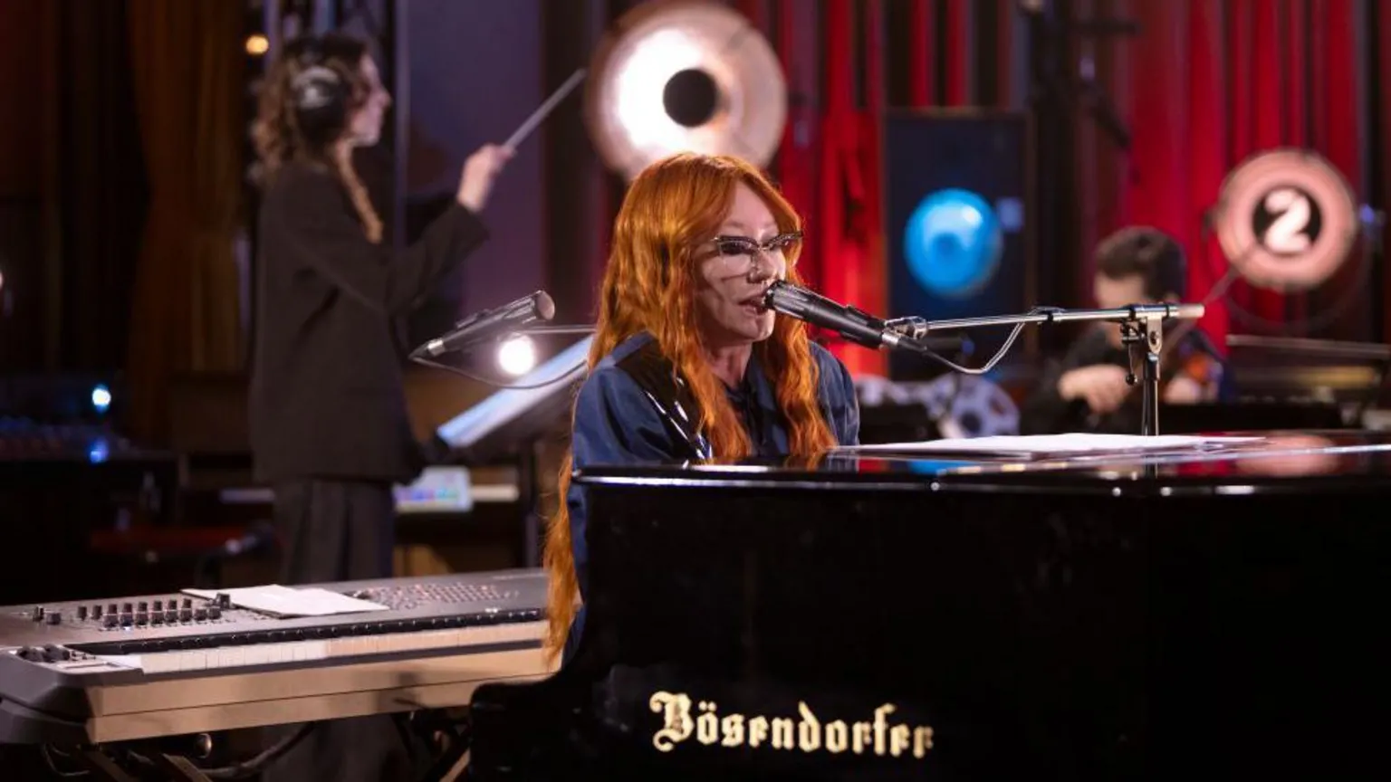 Tori Amos - a woman with long red hair, sitting playing a piano