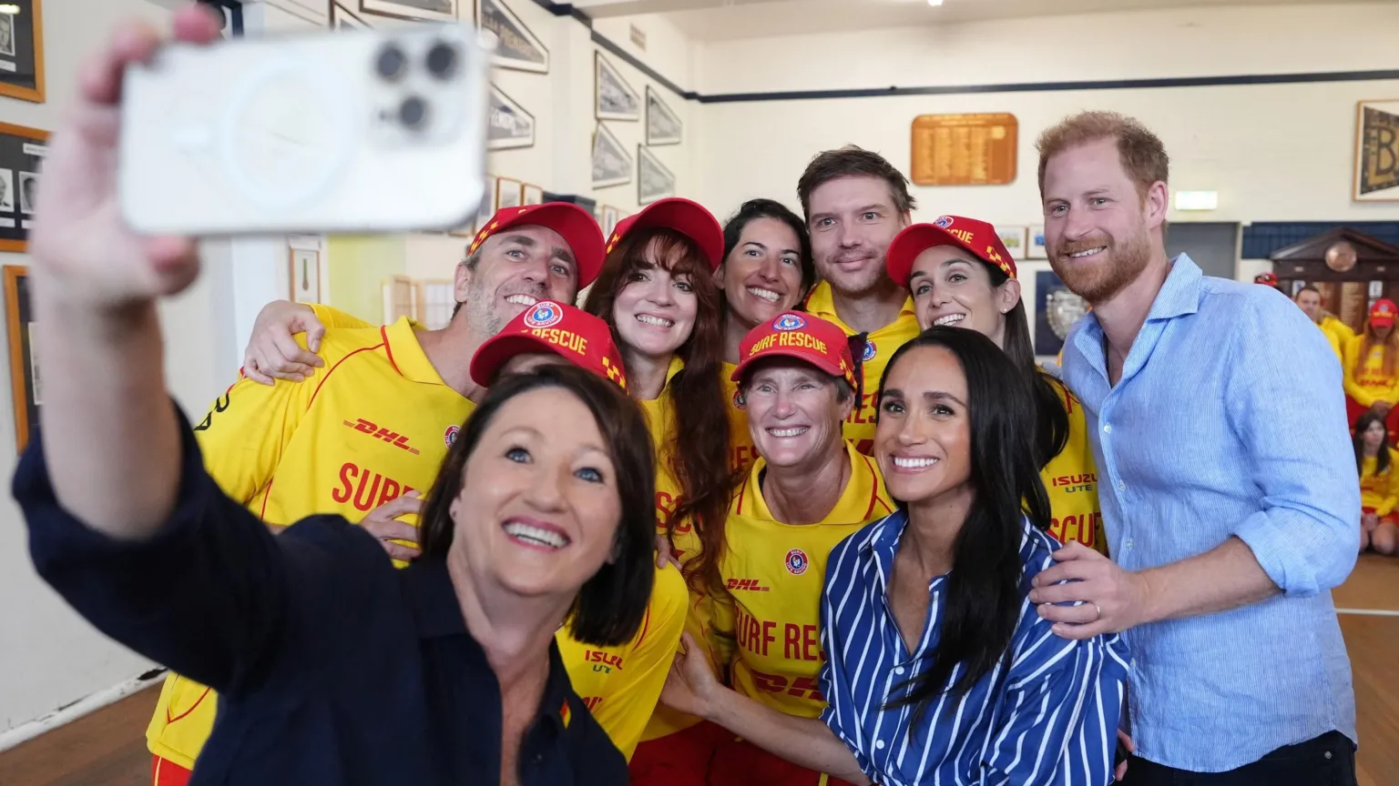  The Duke and Duchess of Sussex pose for a selfie photo as they meet volunteer first responders from Bondi Surf Bathers' Life Saving Club