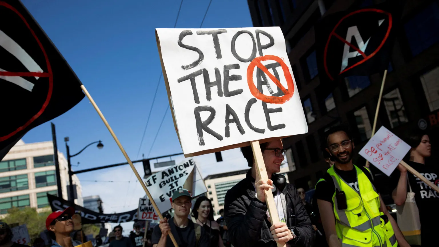  People march through San Francisco, USA, carrying placards against AI. They are smiling on a sunny day and one man wears a high visibility vest.