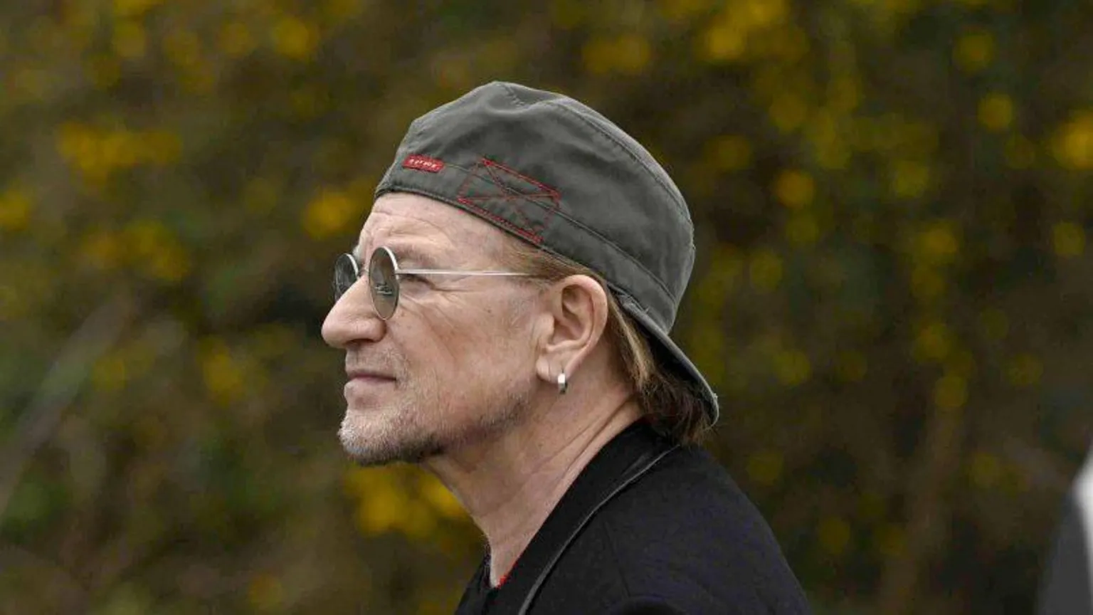 PA Shows Bono with baseball cap back to front and wearing glasses