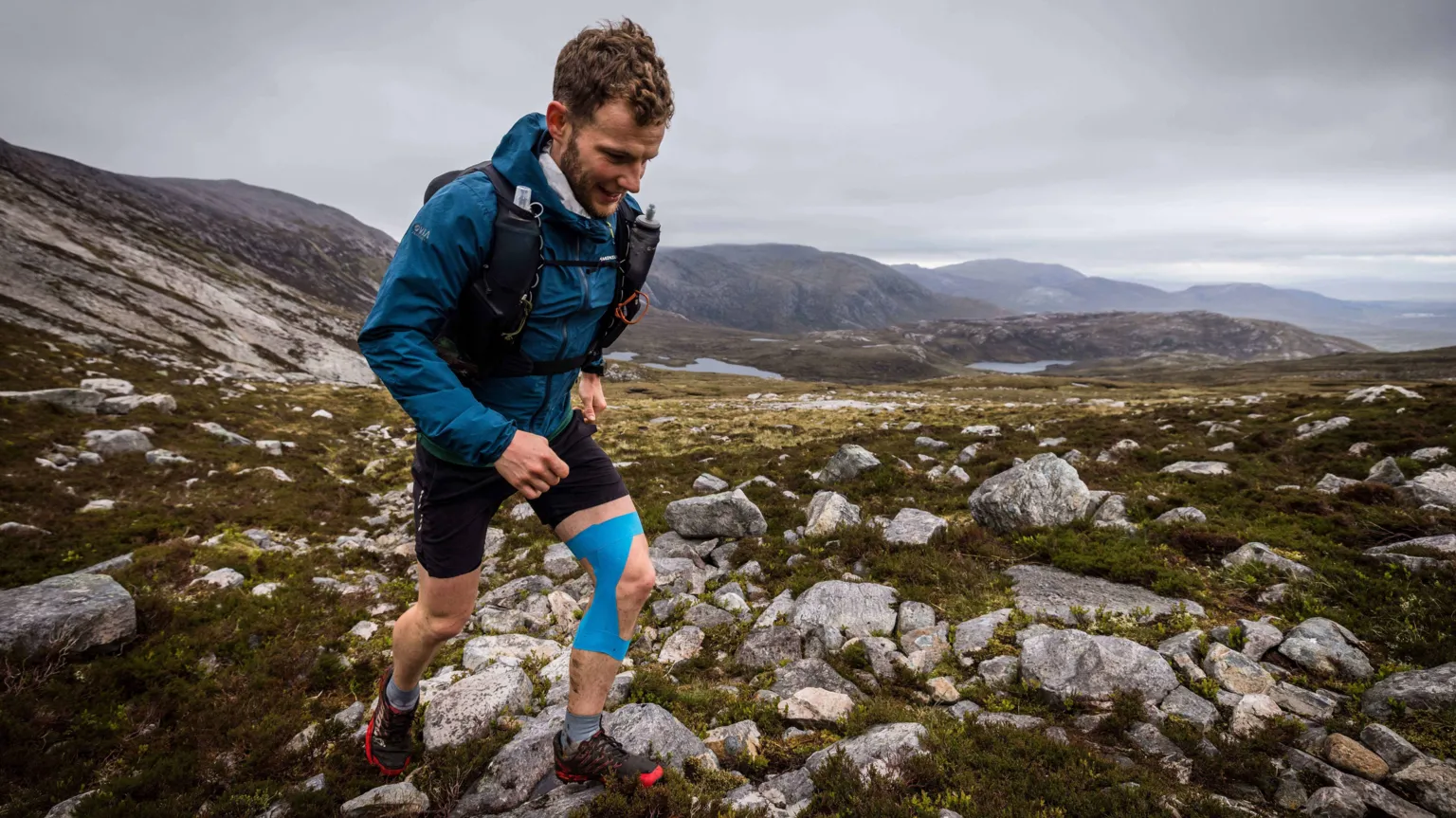 No Limits Photography David Parrish in blue running gear in the hills. He is smiling.