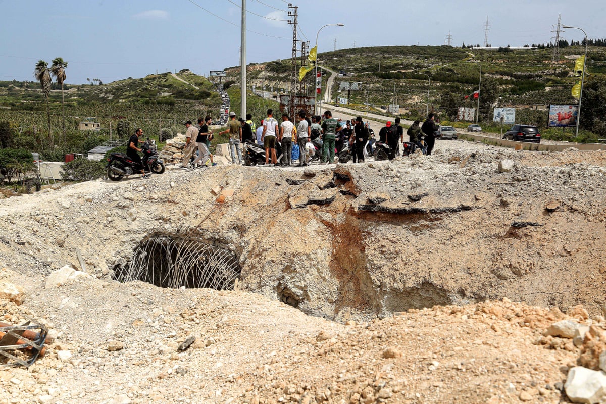 Lebanese people wait to cross over the remains of a bridge blown up by Israeli forces