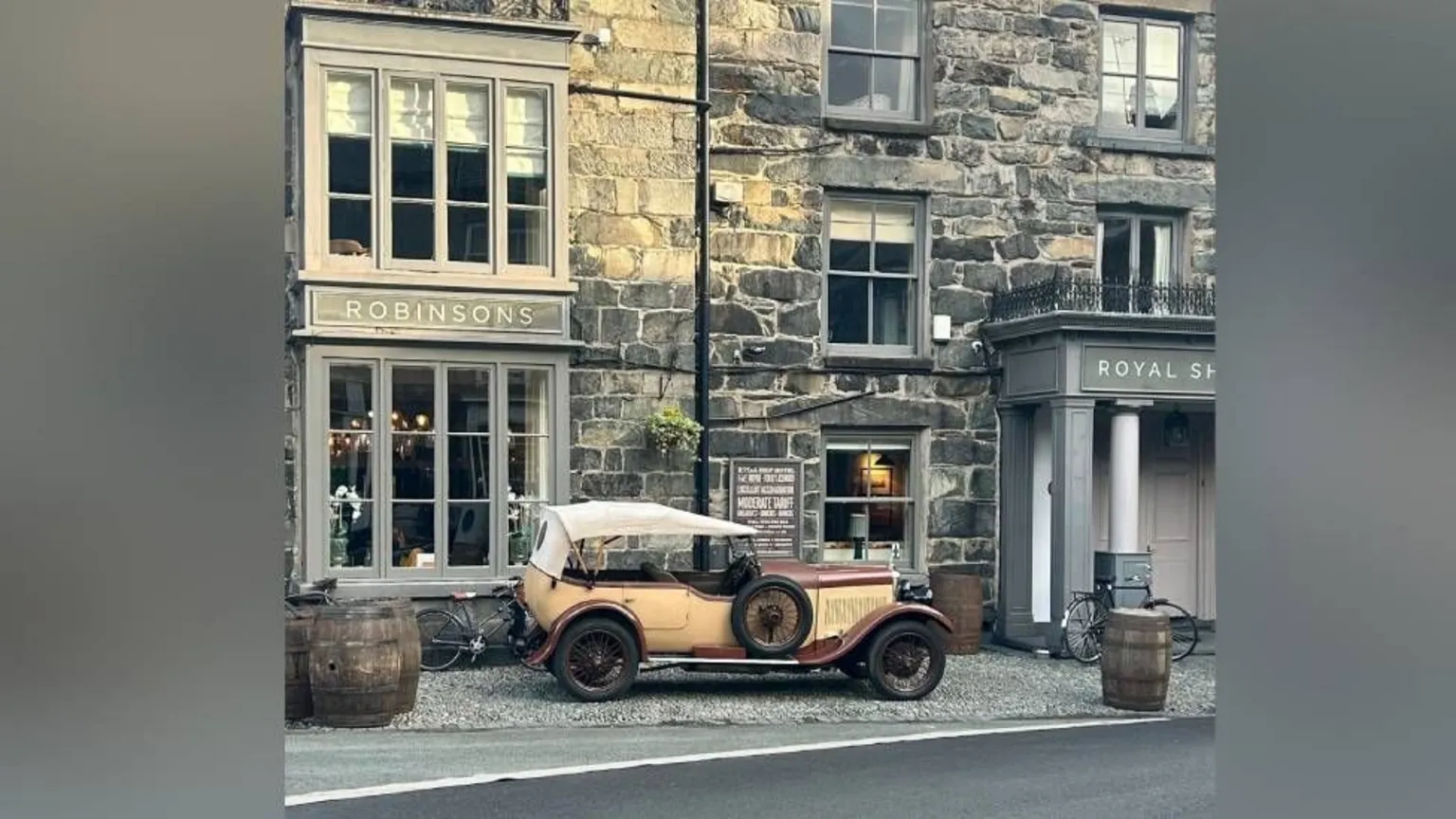 Nia Wyn Evans An old car is parked by a historic hotel. 