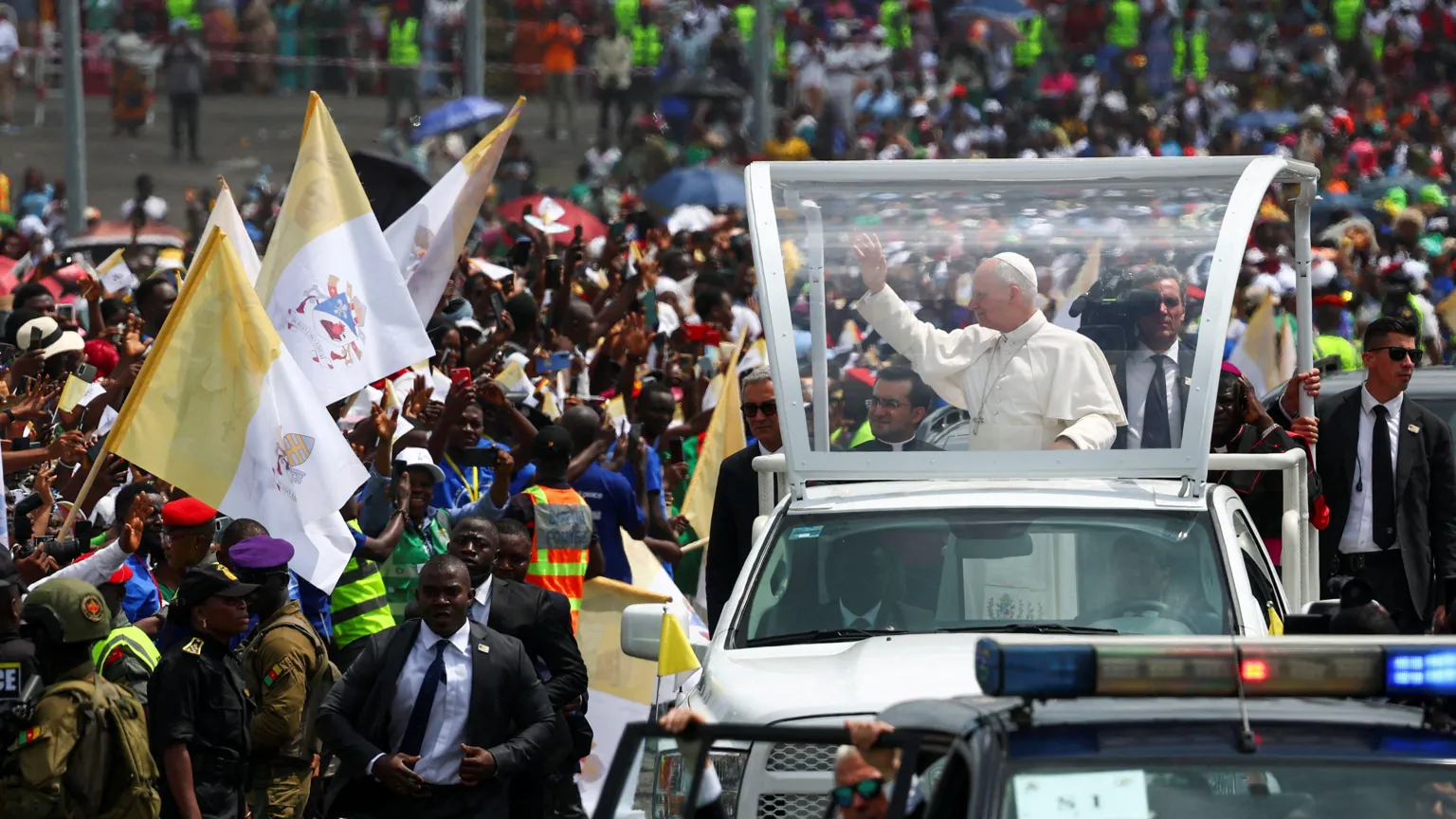  Pope in his vehicle on the right, waving to crowds that are on the left of the picture
