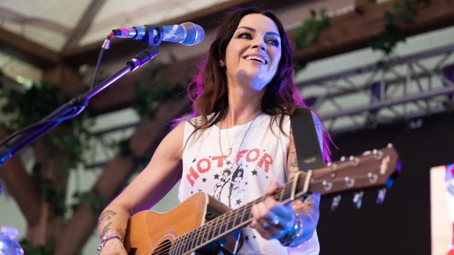  Amy Macdonald performing onstage, wearing a white T-shirt and playing an acoustic guitar