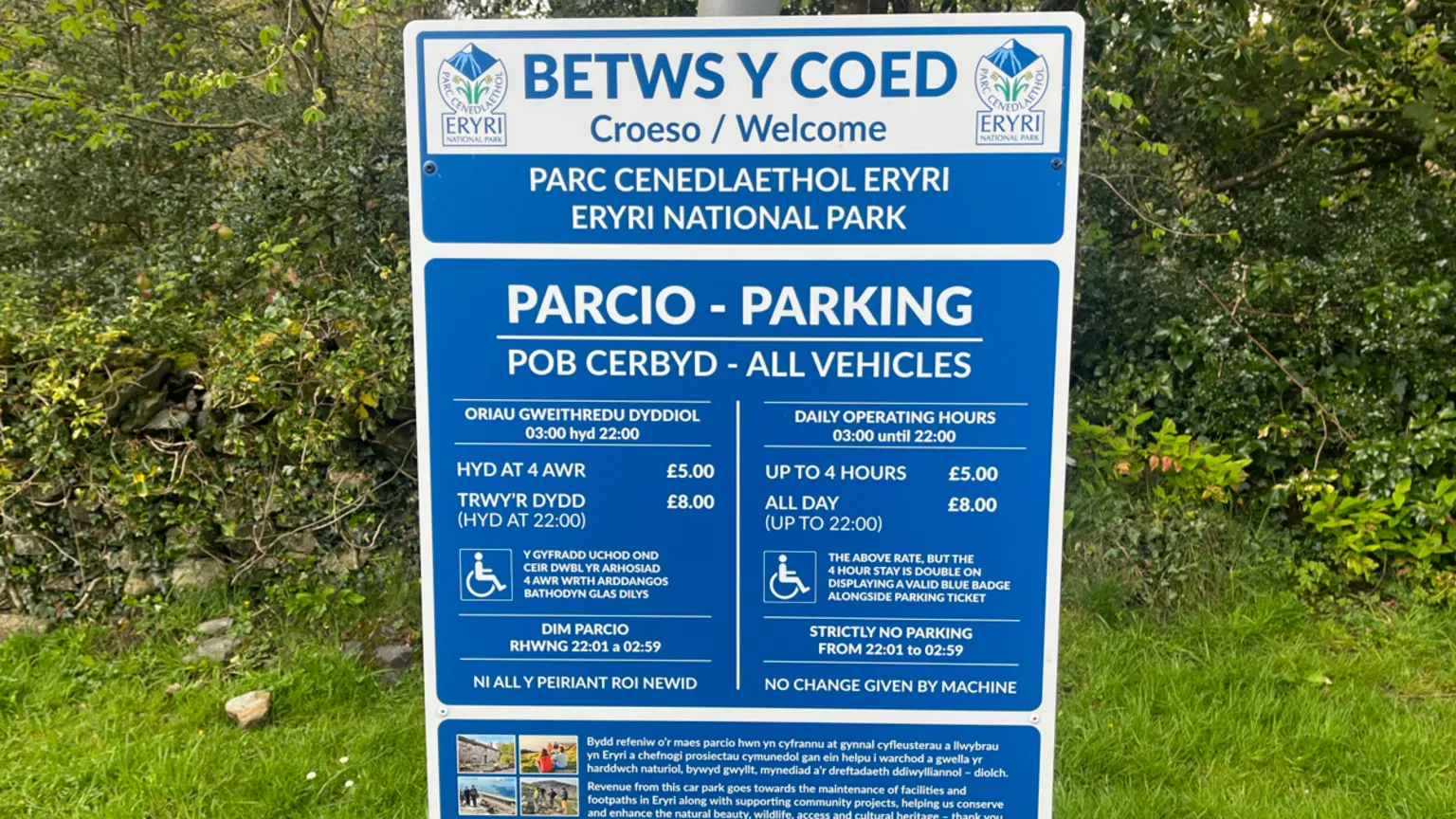 A blue sign for a car park in Betws-y-Coed lists the rules, fees and restrictions.