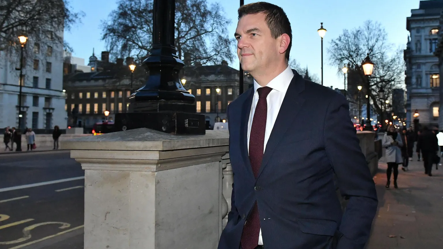  Sir Olly Robbins wears a navy suit as he walks down Whitehall at dusk