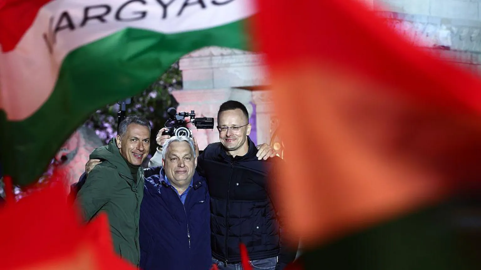 NurPhoto via Three men link arms behind red and green flags