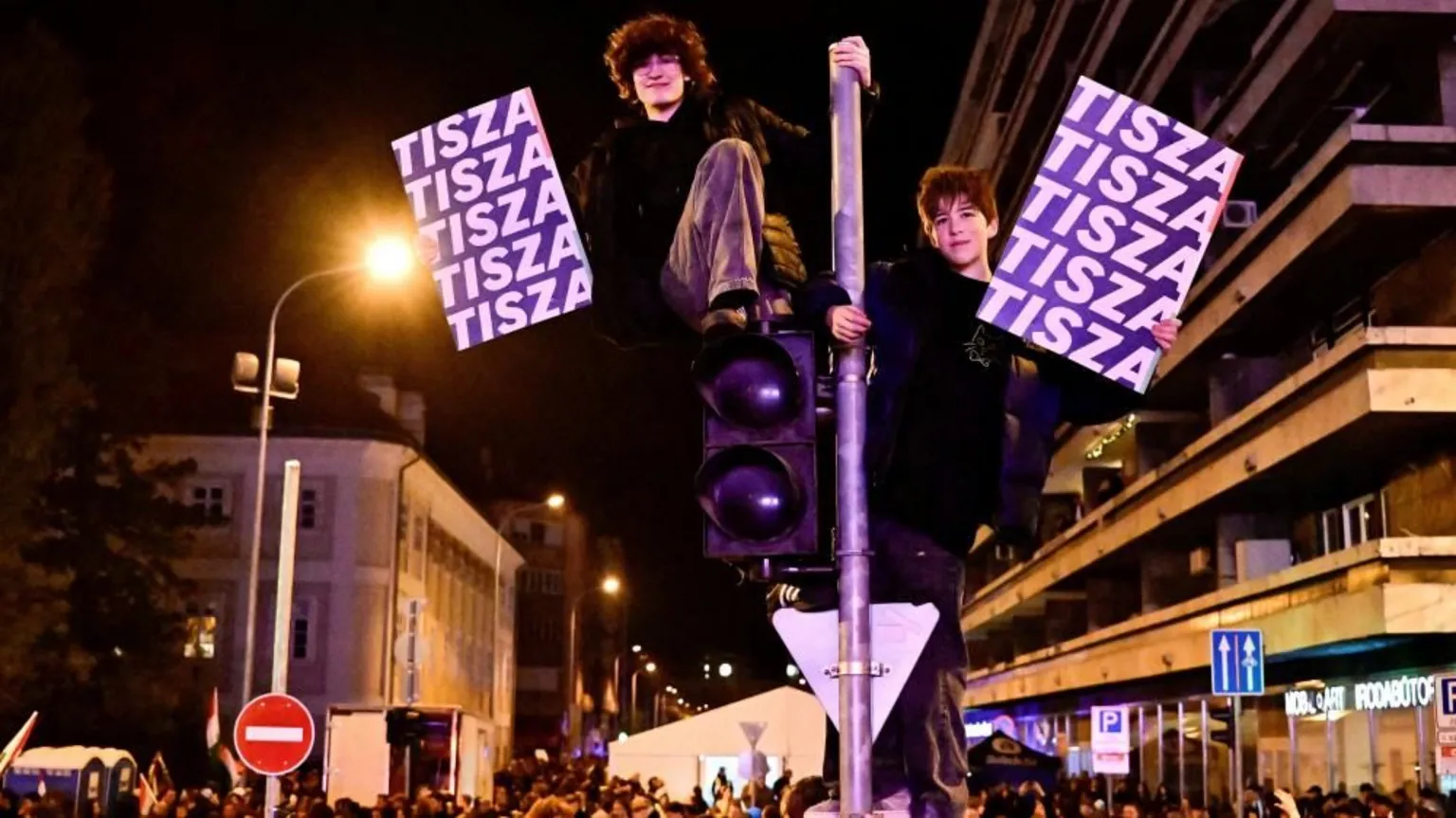 People hold signs with the name of the opposition Tisza party as others gather after the announcement of partial results of the parliamentary election, in Budapest, Hungary