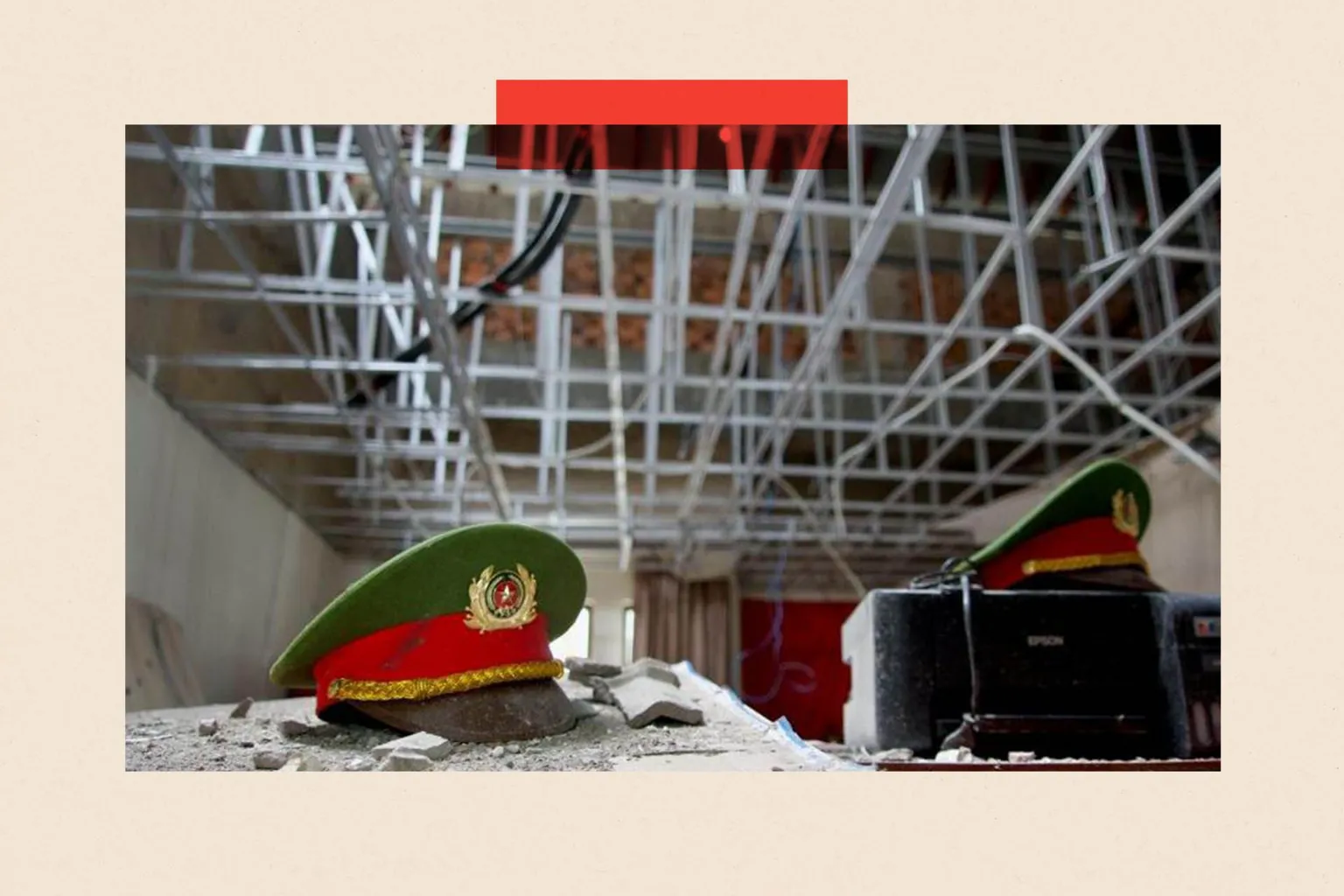 LULU LUO/BBC Two red and green police hats with gold crests on them on a desk in a derelict building