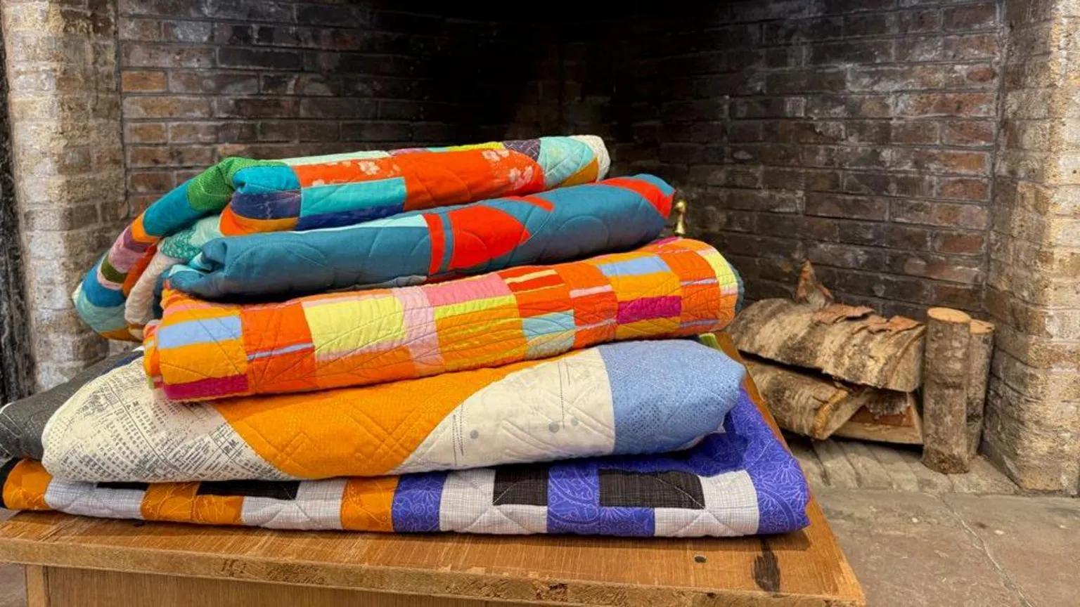 BMQG A pile of quilts in front of a fire place
