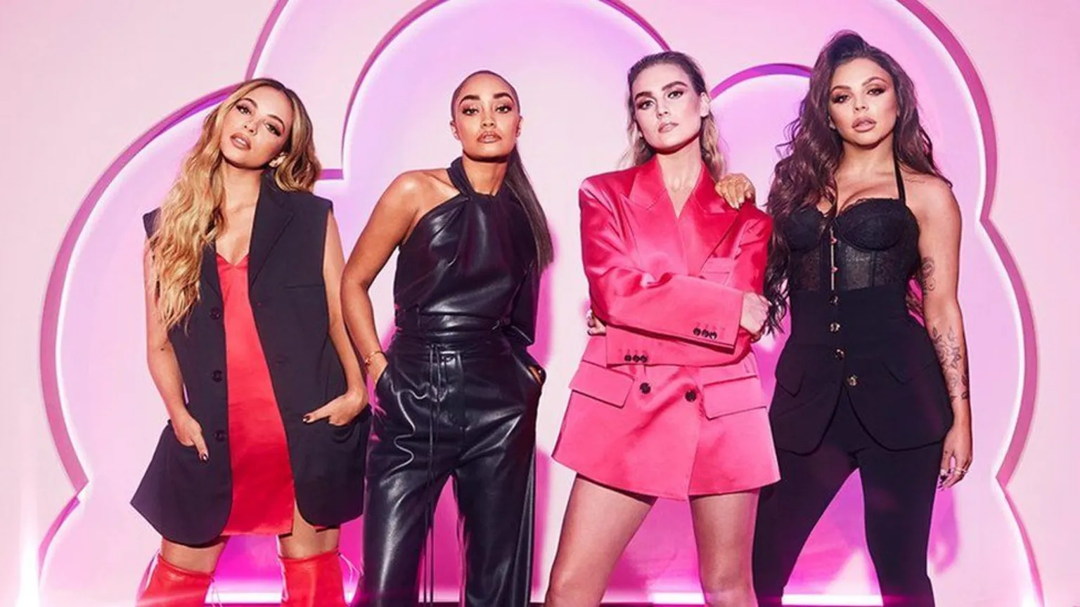 The four members of Little Mix stand side by side wearing fashionable black and red fashion outfits in front of a pink backdrop