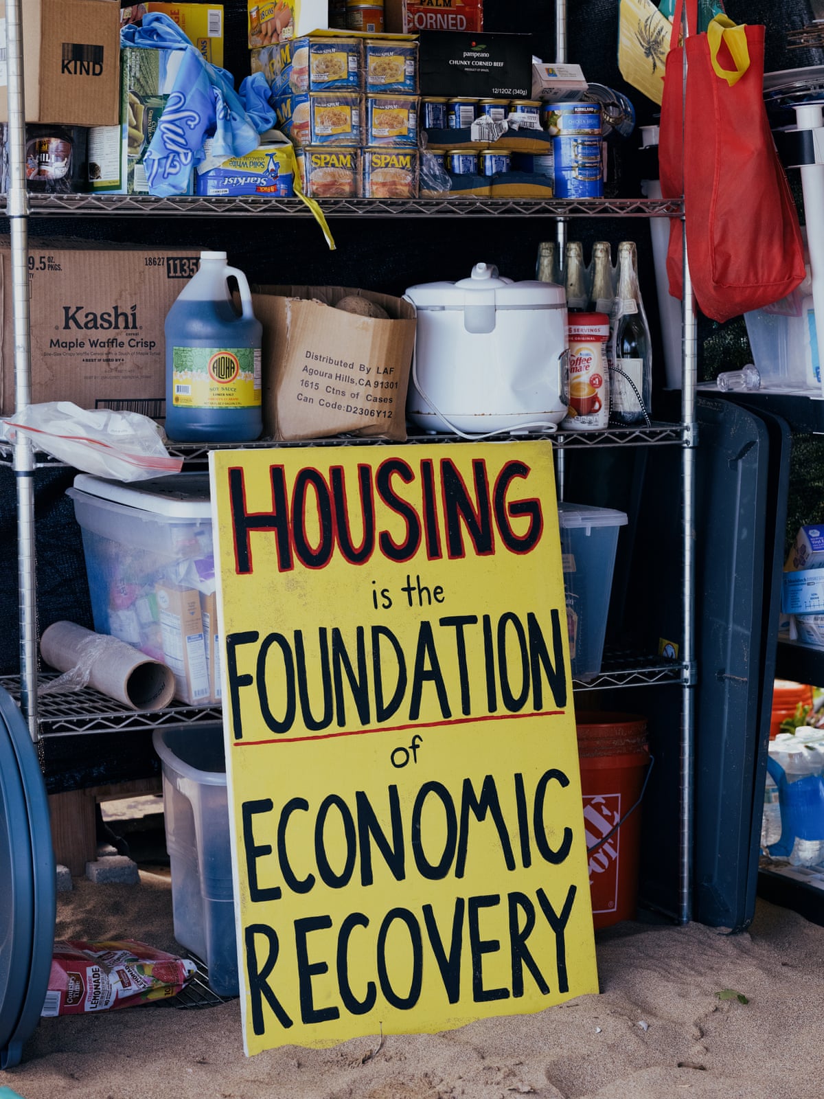 A protest sign that reads ‘housing is the foundation of economic recover’ rests against a shelf of cleaning supplies and boxes