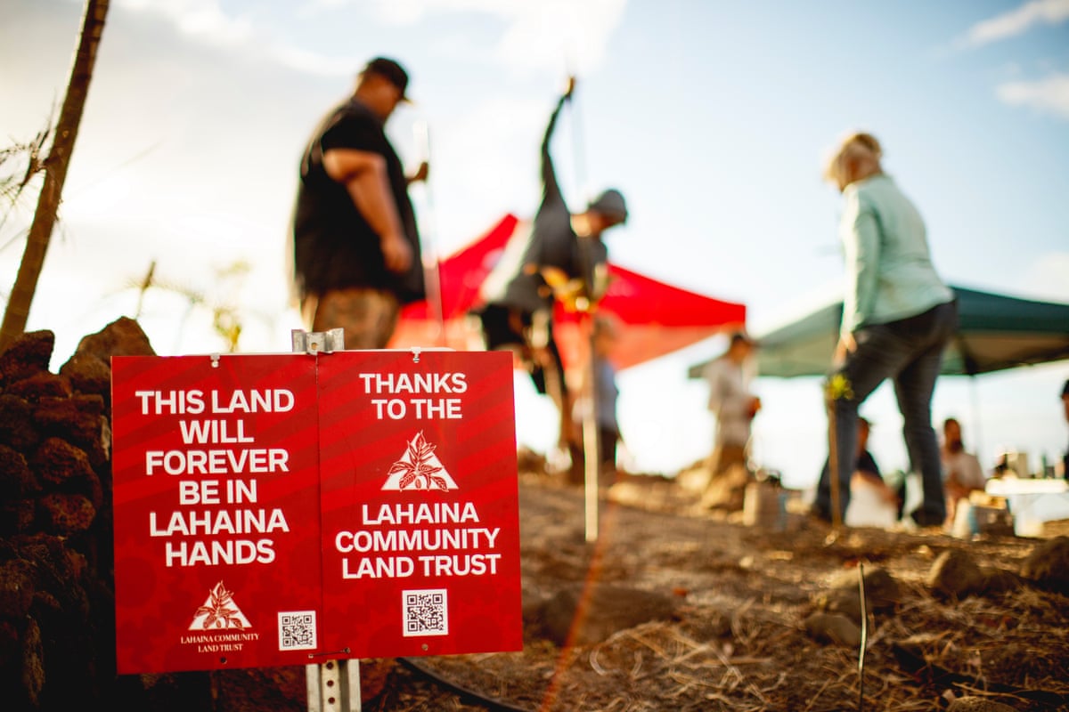 three volunteers working in front of a small sign that says ‘this land will forever be in Lahaina hands’ and ‘thanks to the Lahaina Community Land Trust’