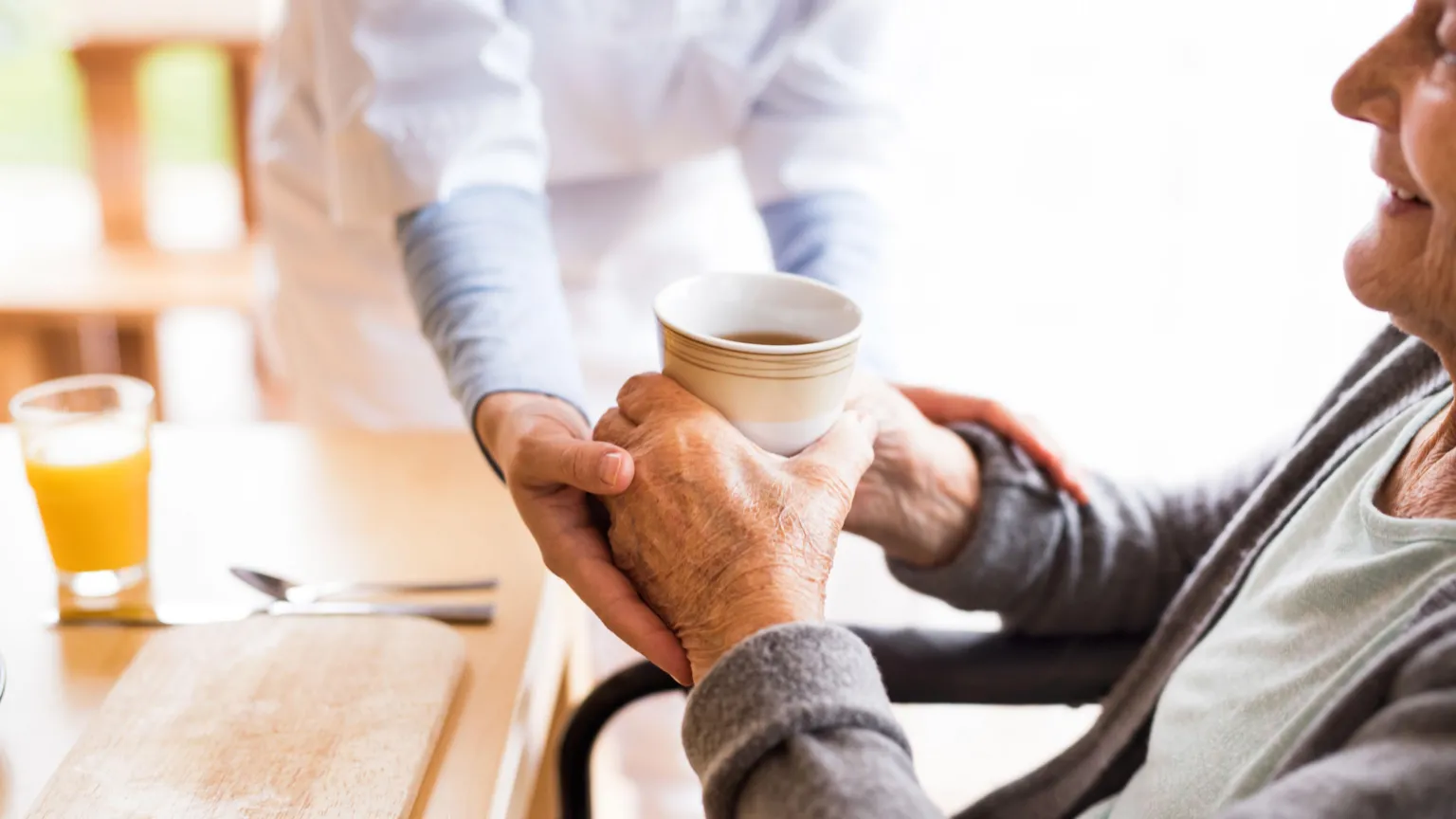  Social carer helps a lady have a drink 