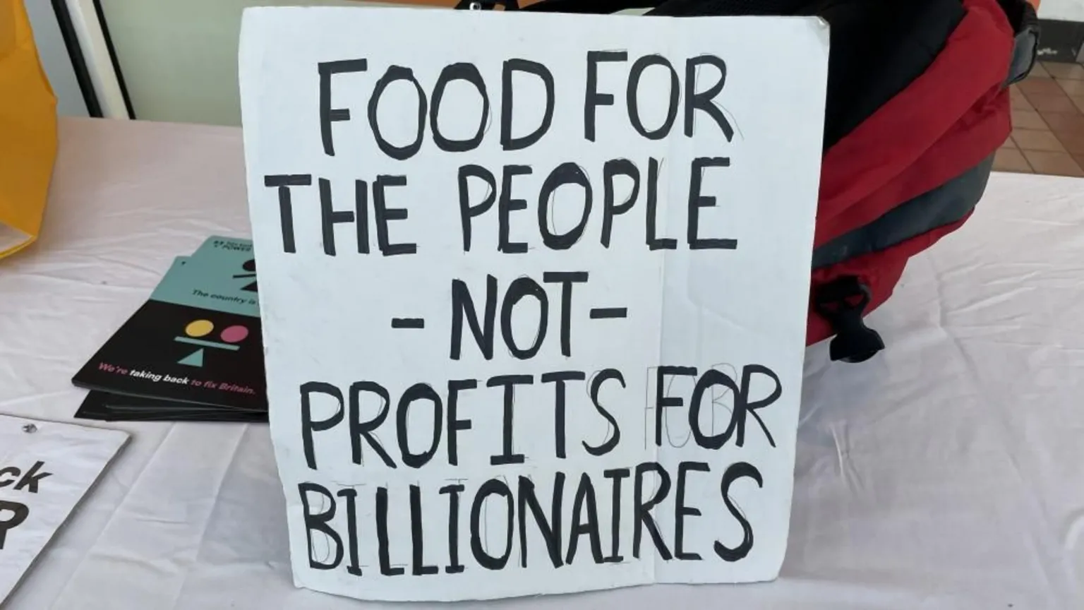  A paper sign which reads: Food for the people, not for profits and billionaires.