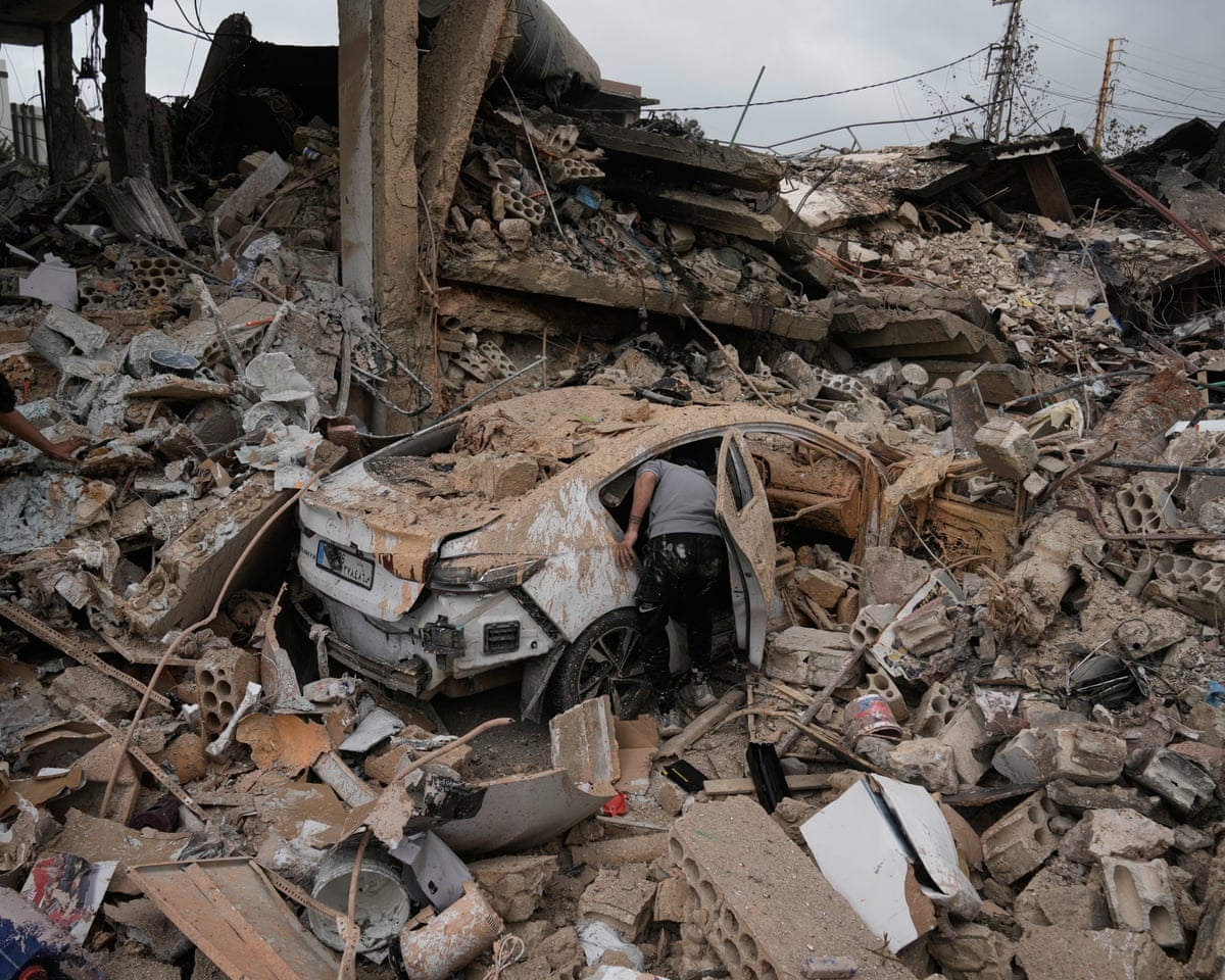 A man inspects a car destroyed in a previous Israeli airstrike during a ceasefire between Hezbollah and Israel in Tyre, southern Lebanon.