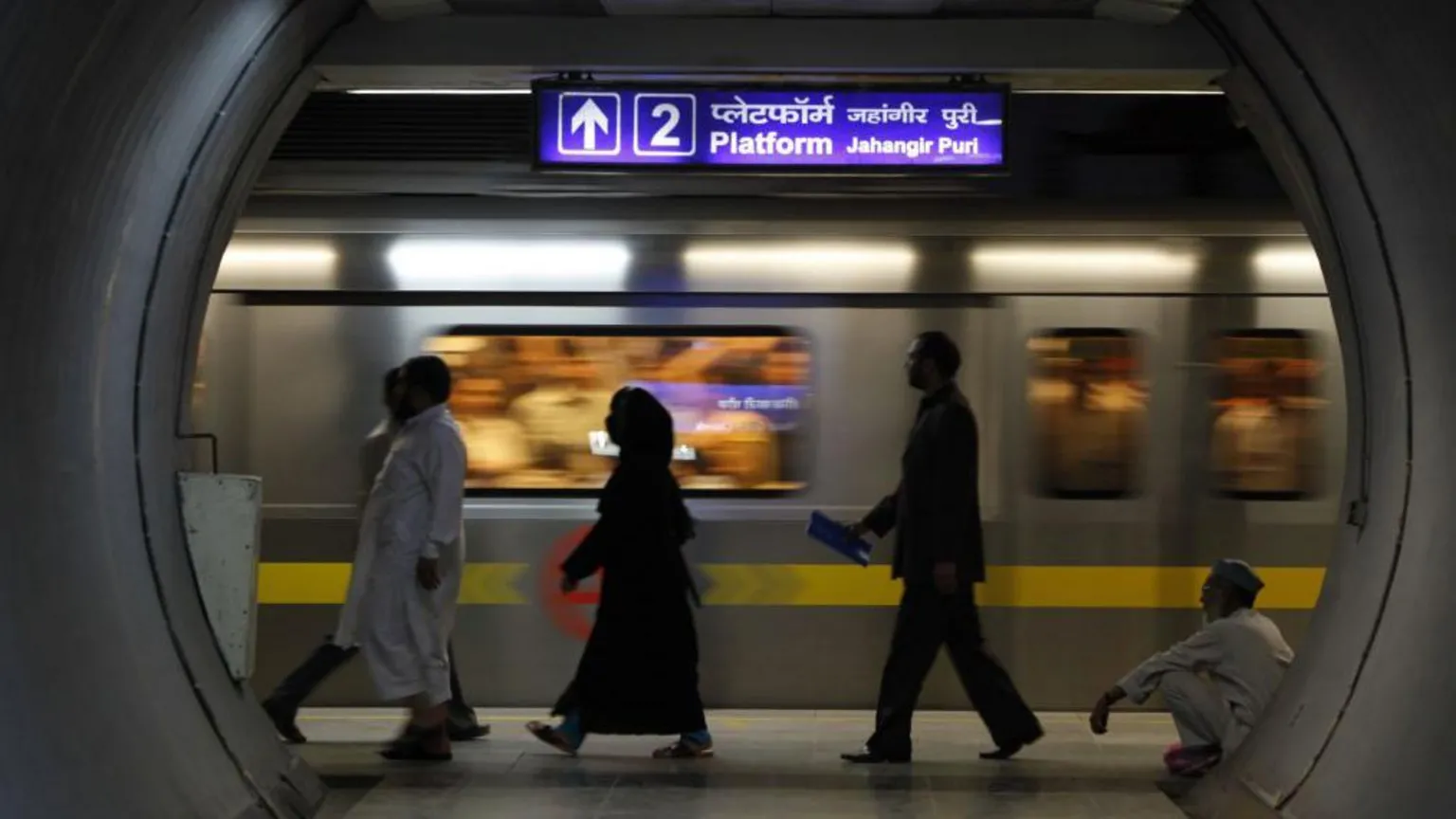 Universal Images Group via The silhouette of men and women walking on a platform at Jahangir Puri metro station in Delhi. 