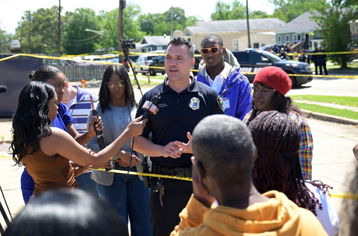 officer speaks to group of people holding microphones outside