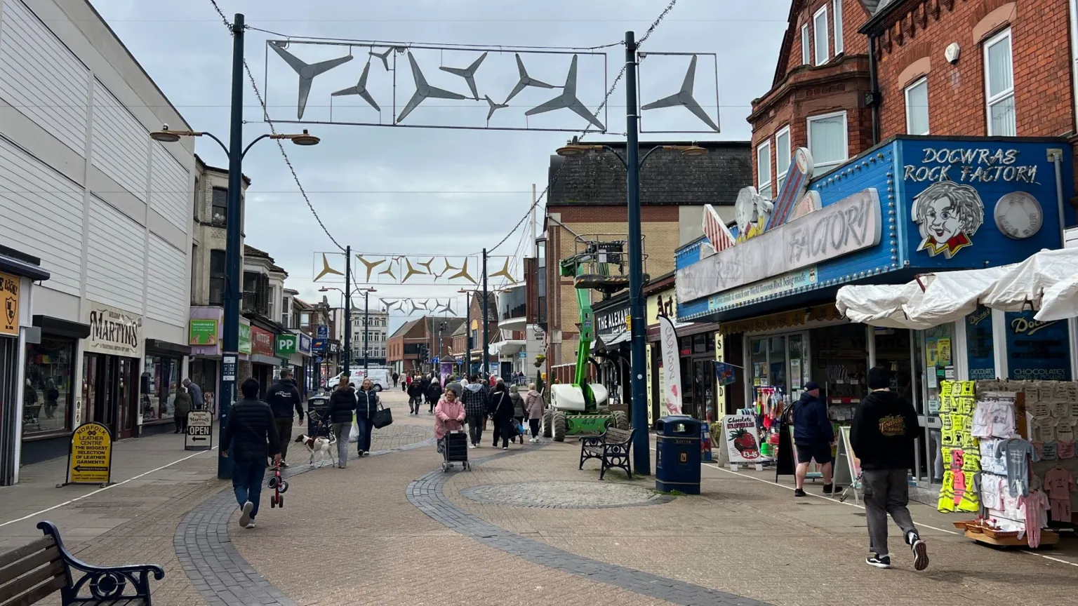Owen Sennitt/BBC People walk along a pedestrianised street lined by shops on a grey day in April