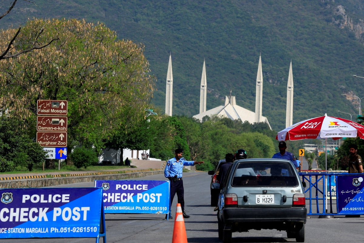 Pakistani police officer gestures to a vehicle