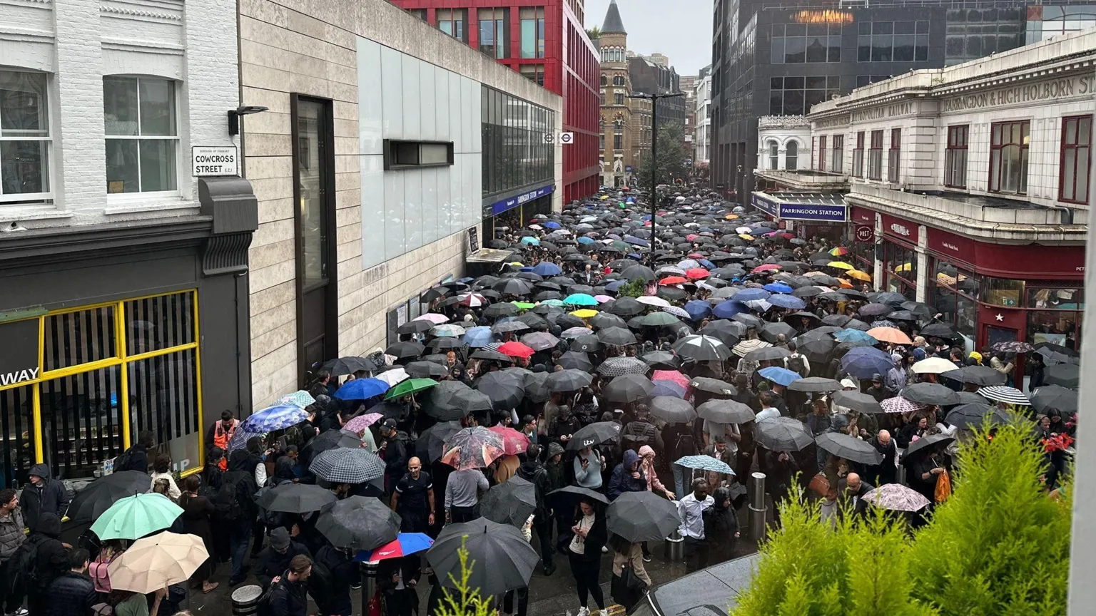  Commuters clash their umbrellas as they huddle into one of the capital's few open stations on Wednesday, Farringdon on the Elizabeth line.