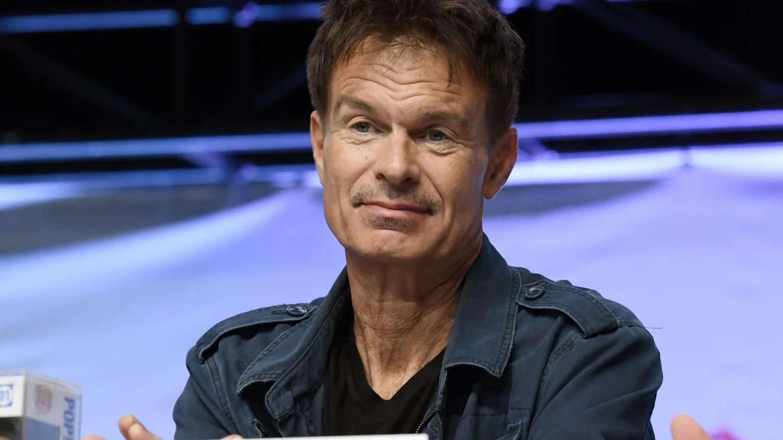  Patrick Muldoon at Comic Con last year, he is wearing a navy combat-style jacket and a black T-shirt