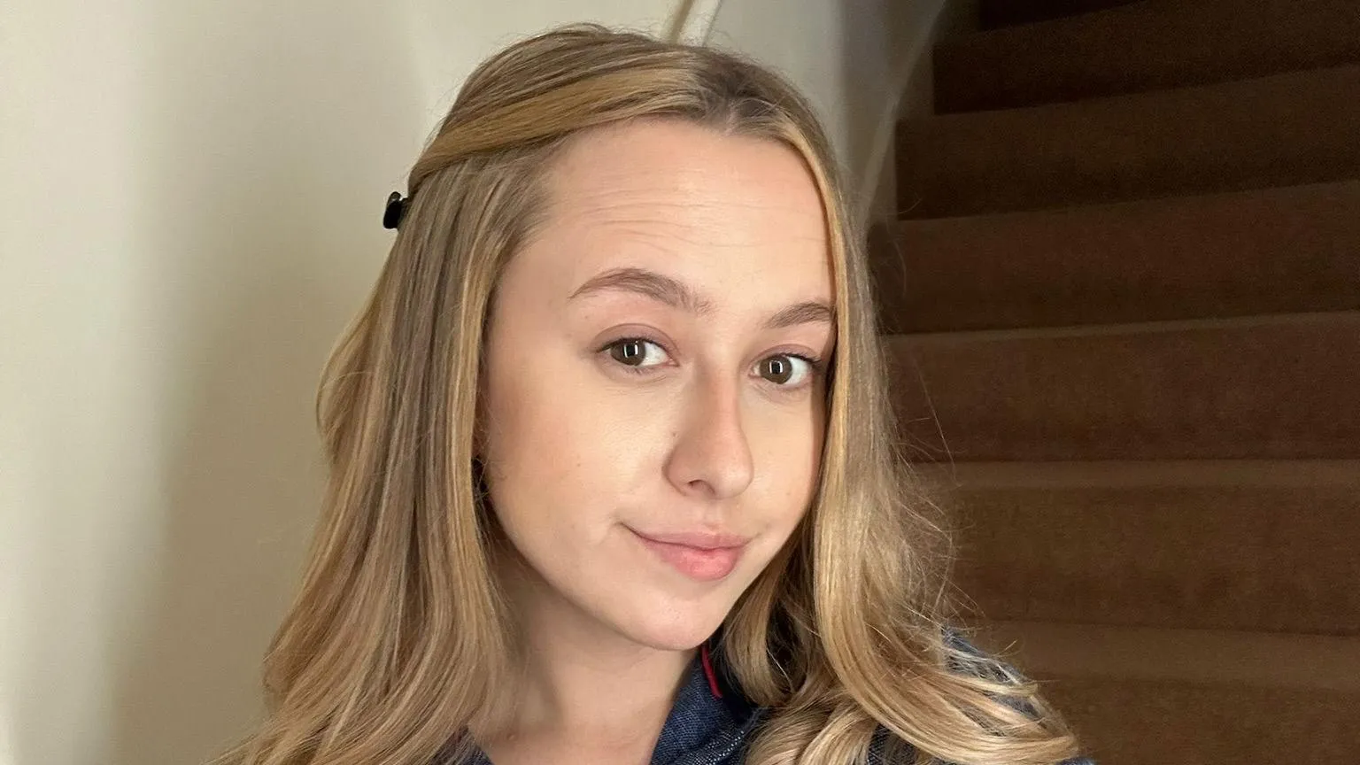 Cait Yardy A selfie of Cait with blonde hair with wooden stairs behind her