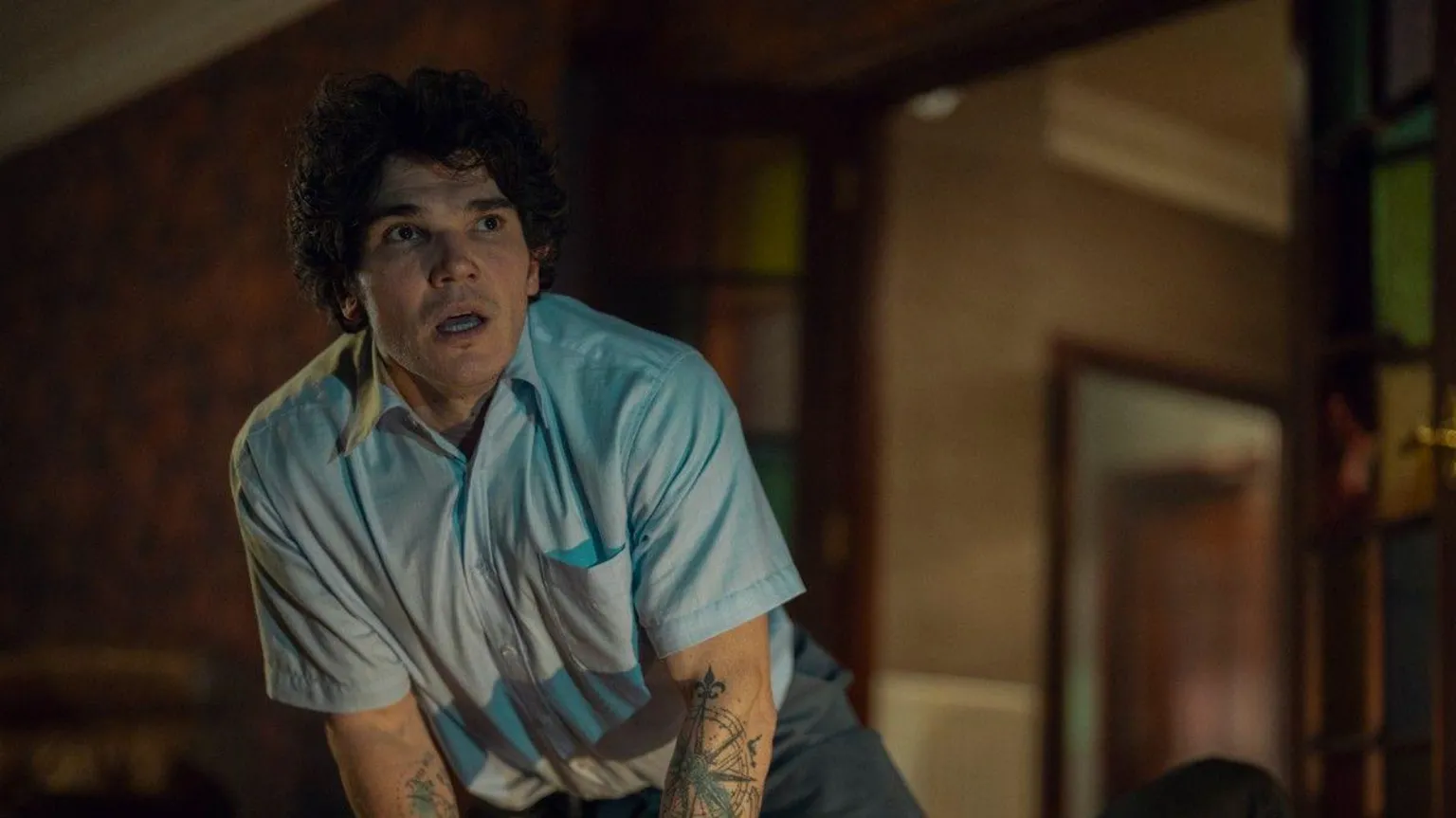 Netflix Fra Fee, wearing a short sleeve blue shirt. He has short, curly brown hair. 