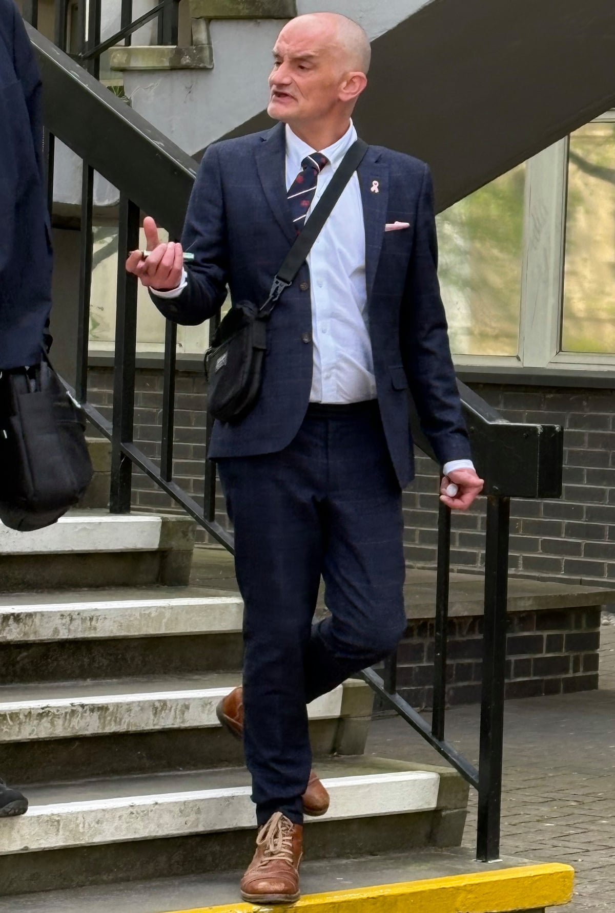 A suited Lee Owens on steps outside court