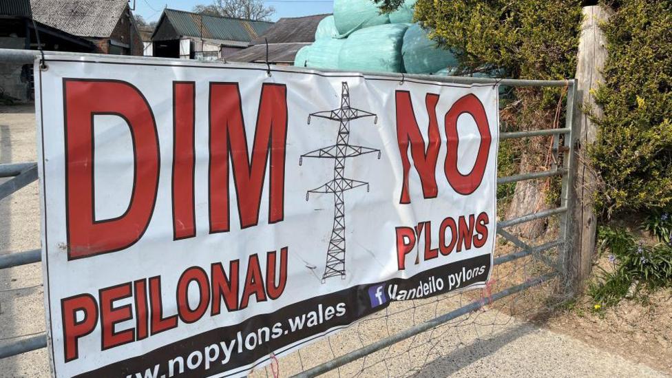 Arwydd ar giat fferm yn amlygu gwrthwynebiad i'r posibilrwydd o osod peilonau yn ardal Llandeilo