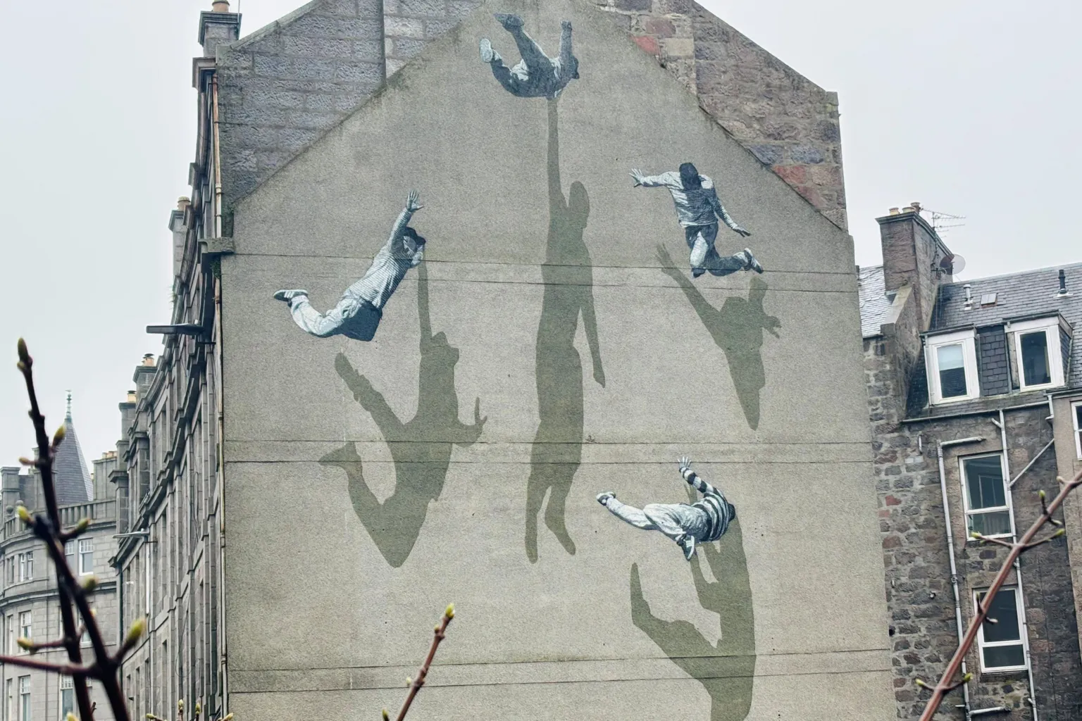 Art work on a building wall showing four people and their shadows.