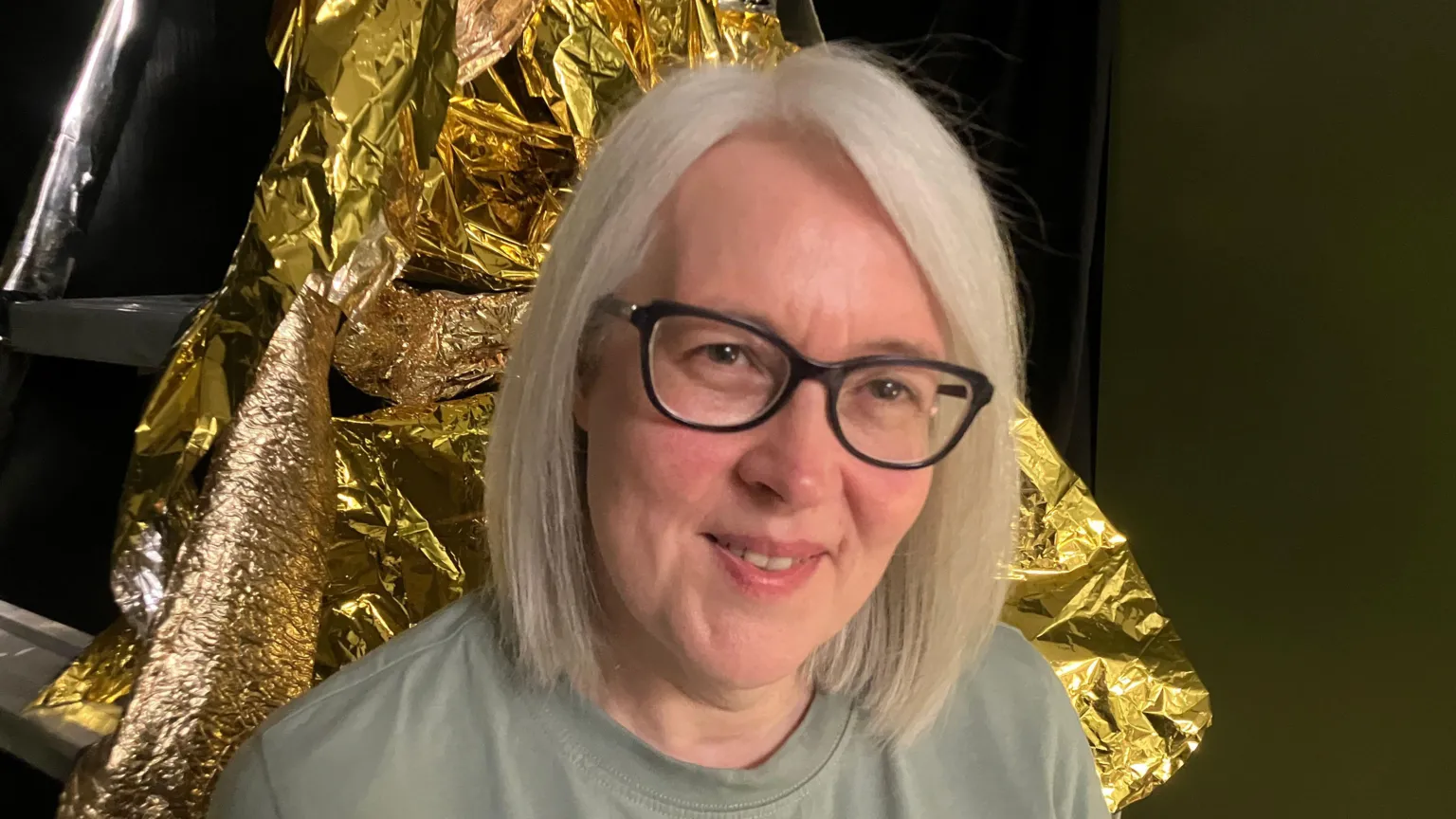 Jane McKnight A woman, pictured from the shoulders up, smiling at the camera. She is wearing a green top and glasses and she has blonde hair. 