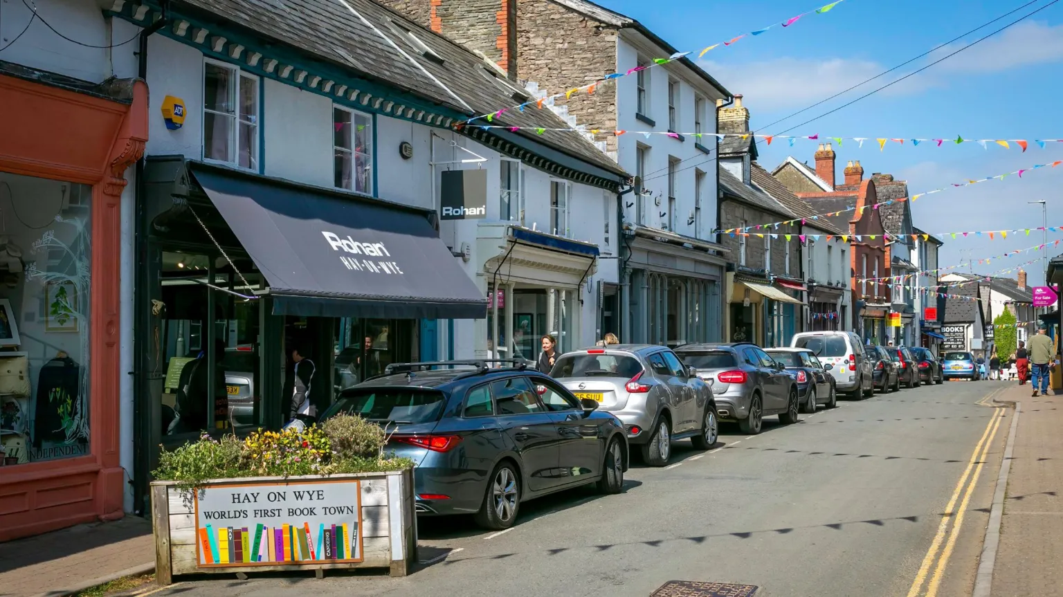 A town's street with ribbons tied across it at roof-level. A sign reads 