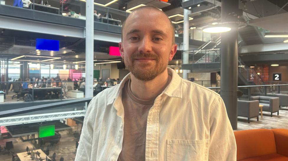 Guto Ifan mewn crys brown a siaced golau