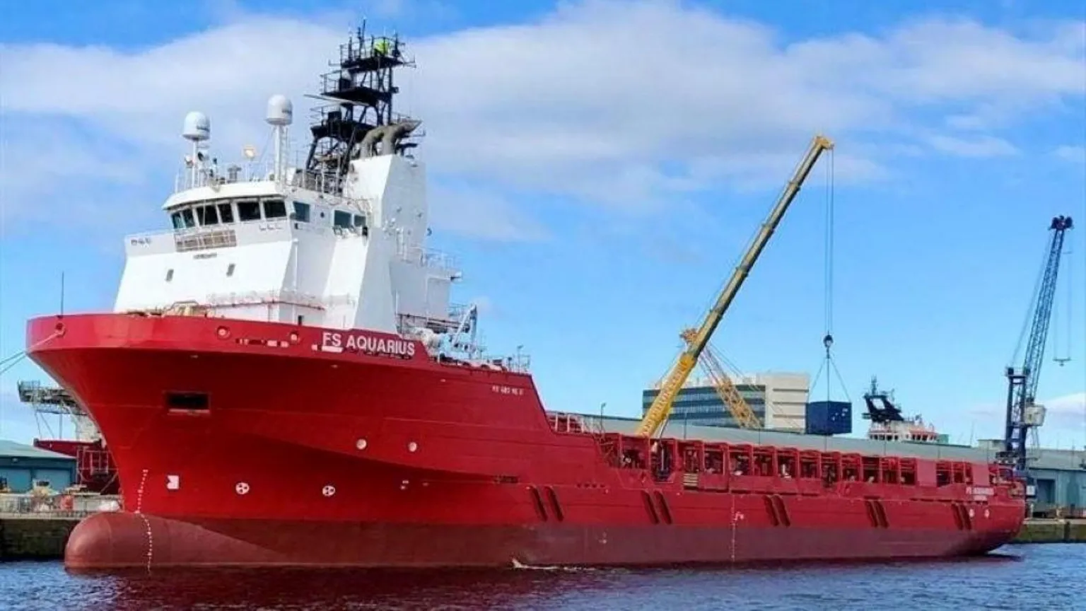 Fletcher Group The red-hulled offshore vessel Aquarius, sitting in water, under a blue sky